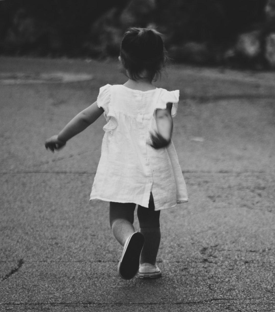 gray scale photography of girl walking towards destination